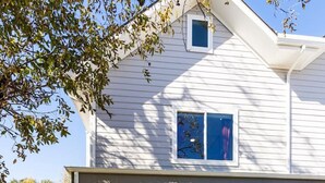 A two-story house with a covered porch, a small front yard, and a visible garage door. - Spacious Austin Home Base| Sleeps 12+ | Near DT (Austin)