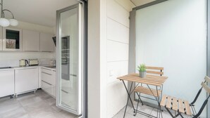 Eine moderne Küche mit weißen Schränken, einer Schiebetür aus Glas und einer kleinen Essecke mit Holztisch und Stühlen.