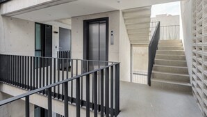 A modern building with a staircase, a metal railing, and a door with an elevator.