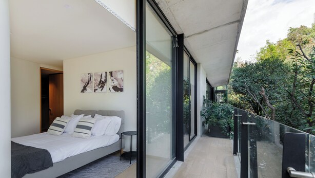 A modern bedroom with a large bed, a small bedside table, and artwork on the wall.