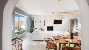 A modern interior with a dining area, white sofa, and a view through an archway to a balcony.