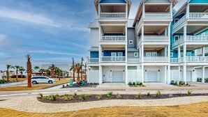 A multi-story residential building with balconies, a driveway, and palm trees. - Gorgeous family beach home with beach & gulf views, balconies,  pools, & golf (Port Aransas)