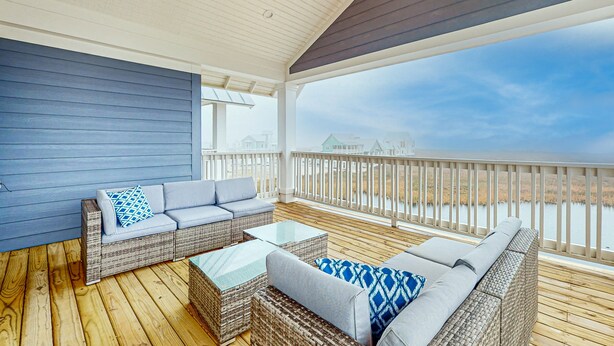 A covered outdoor seating area with wicker furniture and a view of the water. - Gorgeous family beach home with beach & gulf views, balconies,  pools, & golf (Port Aransas)