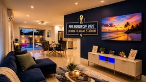 A modern living room with a large TV, a dining area, and a view of a pool. - 5 Star Tropical Pool Near Beach & FLL (Pompano Beach)