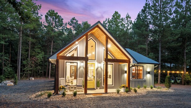 A cozy cabin with a large front porch, wooden beams, and a wrap-around deck.