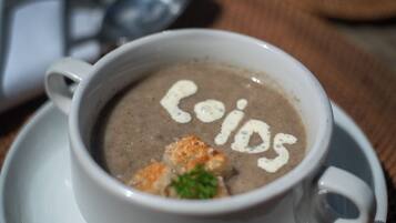 Eine Suppentasse mit Garnitur und Löffel auf einer weißen Untertasse.