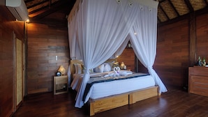 A wooden room with a bed under a canopy, a nightstand with a lamp, and a wooden dresser. - Loid's di Lempuyang (Karangasem)