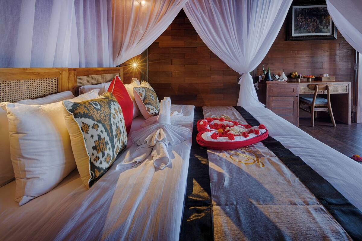 A bedroom with a bed, pillows, a bedside table, a desk, and a chair.