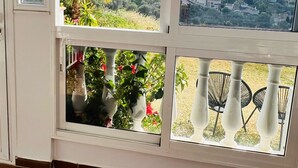 A room with a large window overlooking a hillside with vegetation and buildings. - Vacation apartment in Torrox-Park. Modern, bright, cozy, quiet, dogs welcome. (Torrox)