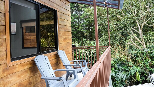 A wooden exterior with a balcony, two chairs, and a glass door.