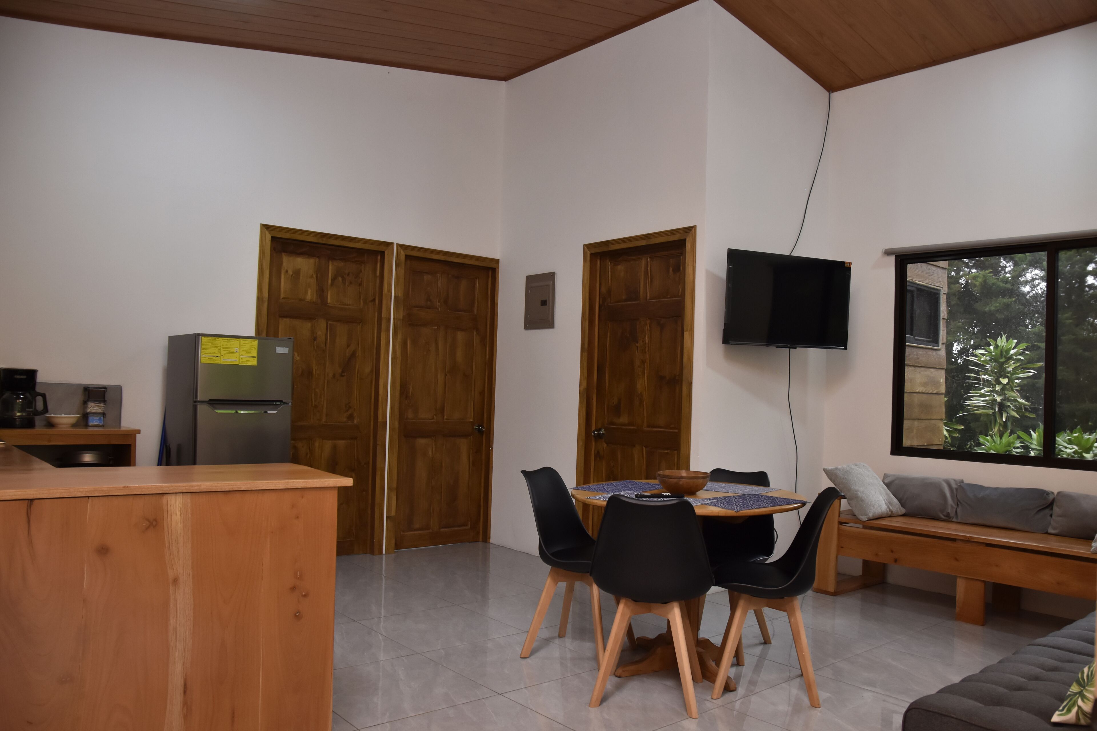A modern kitchen with wooden cabinets, a built-in refrigerator, and a dining area with a round table and chairs.