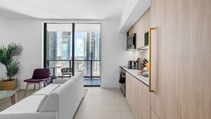 Un apartamento moderno con balcón, cocina y sala de estar con sofá y sillones.