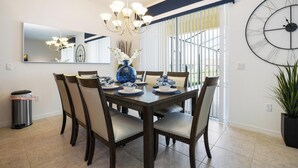 A dining area with a large round clock, a chandelier, and a vase with flowers on the table. - ⛱ Providence Resort - 5★ Golf Community - Lakeview Home – Communal Amenities☀ (Davenport)