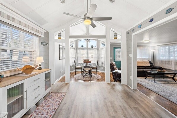 A spacious living area with a ceiling fan, a dining table with chairs, and a sofa.