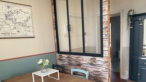 A dining area with a wooden table, chairs, and a vase with flowers. A map is on the wall, and a mirror reflects the room. - Bright apartment near the quays, ideal for discovering Quimper! (Quimper)