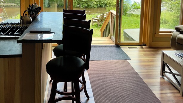 Une cuisine moderne dotée d’un grand îlot central, de tabourets de bar et offrant une vue sur une rivière et la verdure environnante.