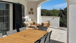 A sunlit patio with a wooden table and chairs, a sofa, and a potted plant. - Luxury 8-person Villa with pool and sea view (Soalheira)