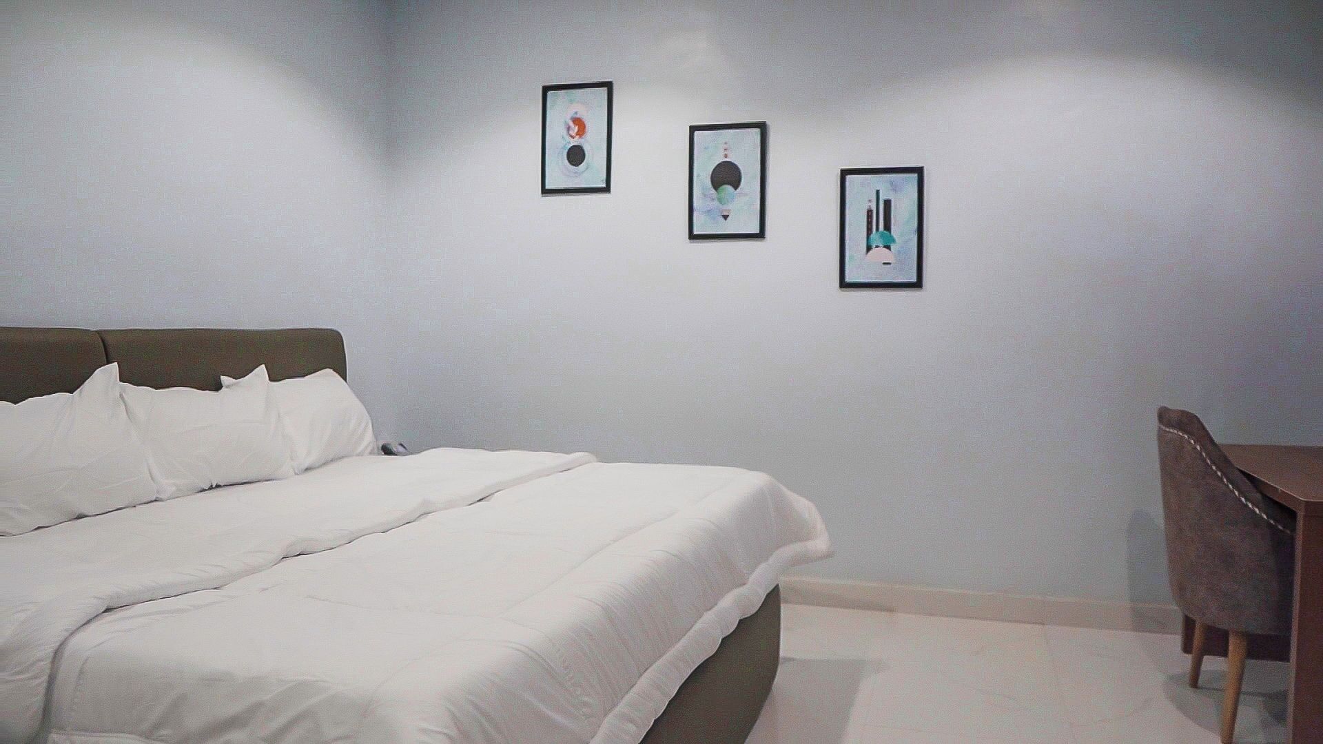 Un dormitorio con una cama, un escritorio y tres obras de arte enmarcadas en la pared.