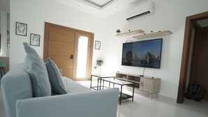 A modern living room with a sofa, TV, and a wooden door.