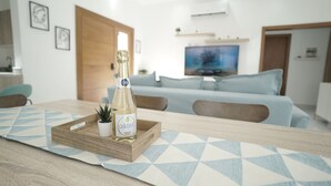A modern living room with a wooden coffee table, a bottle of champagne, and a small potted plant.