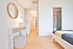 Ein Schlafzimmer mit Bett, rundem Spiegel, Nachttisch mit Lampe und Kleiderschrank.