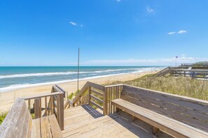 A wooden boardwalk leading to a beach with a clear view of the ocean.