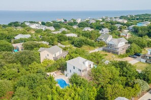 A residential area with houses surrounded by greenery and a visible swimming pool. - Sun Realty pet-friendly oceanside Duck home w/ pool and hot tub (Duck)