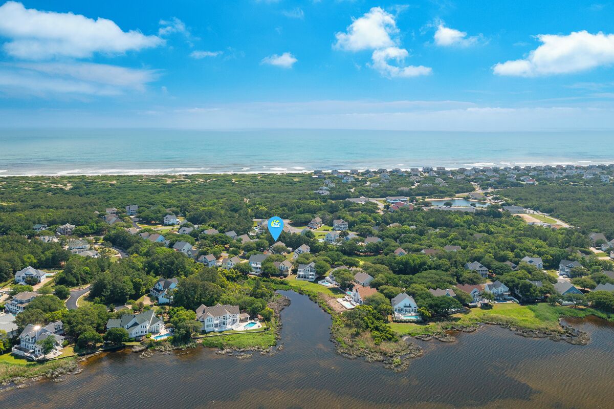 Vue aérienne d’une zone résidentielle côtière, avec des maisons, une rivière et une plage.