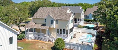 A two-story house with a covered patio and a swimming pool.