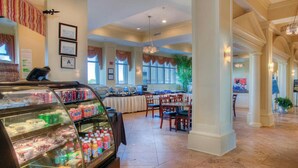 Un hall d’hôtel spacieux avec un comptoir de vente de produits alimentaires, un espace repas et de grandes fenêtres.