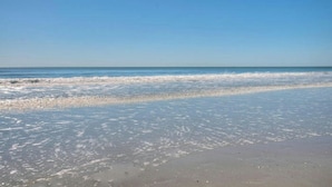Une plage aux vagues douces et sous un ciel dégagé.