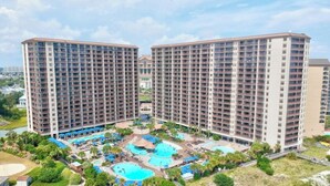 Un hôtel de grande hauteur doté de nombreux balcons et d’une cour intérieure abritant plusieurs piscines et des espaces de détente.