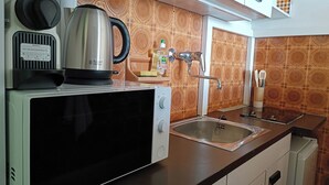Una cucina con forno a microonde, bollitore e lavandino.