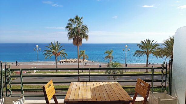 Un tavolo e sedie di legno su un balcone con vista sulla spiaggia e l'oceano.