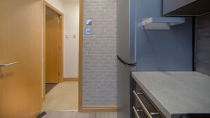 A compact kitchen with a wooden door, a brick wall, and a built-in oven. - Guild Street Apartment | Grampian Lettings Ltd (Aberdeen)