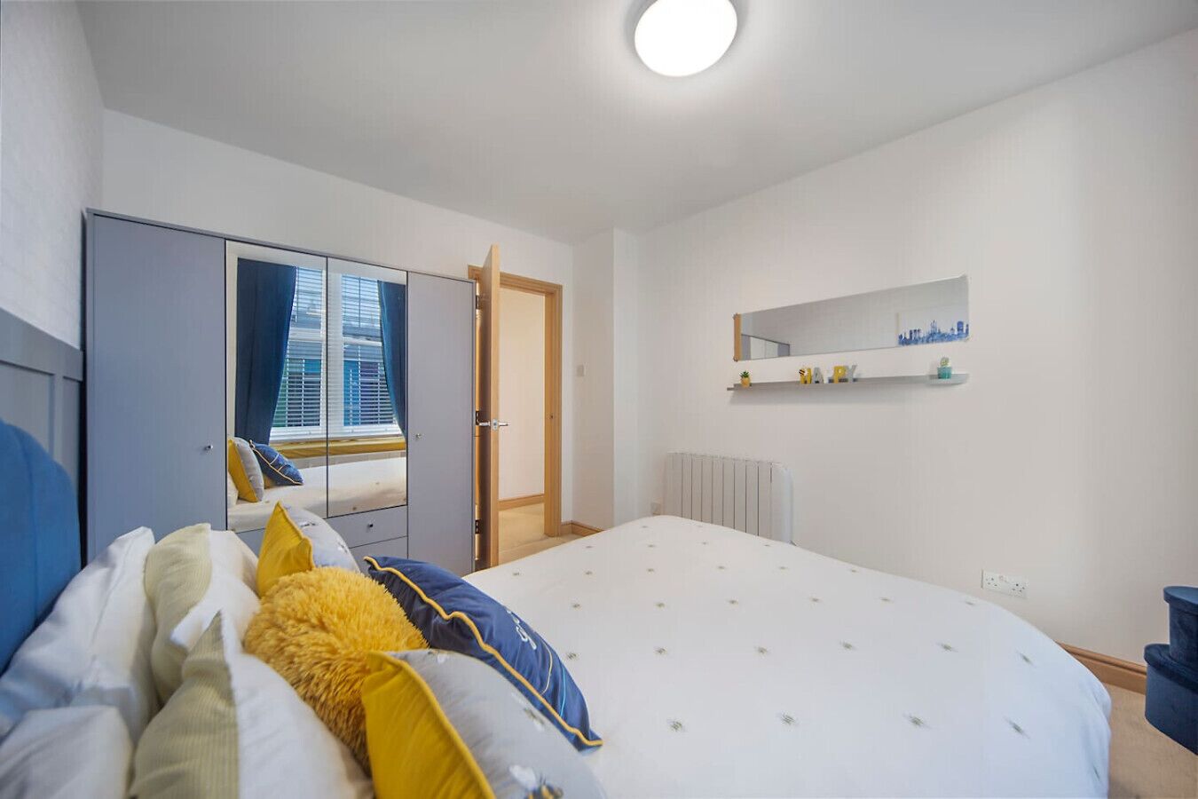 Un dormitorio moderno con cama, armario y espejo en la pared.