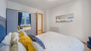 A modern bedroom with a bed, wardrobe, and a mirror on the wall. - Guild Street Apartment | Grampian Lettings Ltd (Aberdeen)