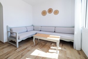 Un salon moderne avec un canapé d’angle gris clair, une table basse en bois et trois éléments décoratifs en fibres tressées accrochés au mur.