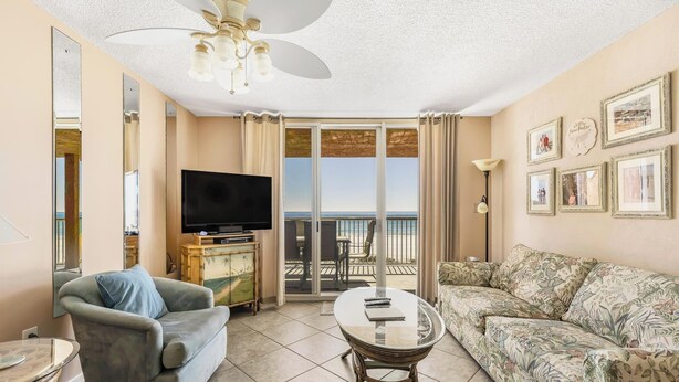 Una sala de estar con sofá, sillón, televisor, mesa y balcón con vistas.