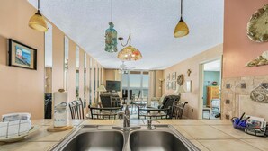 Una cocina con un lavamanos doble, lámparas colgantes y vistas al comedor.