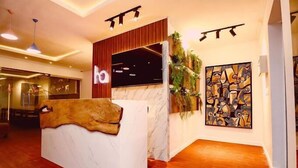 Un espace d’accueil doté d’un comptoir en marbre, de touches de bois et d’œuvres d’art abstraites sur les murs.