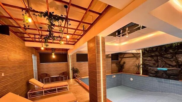 Une piscine intérieure moderne avec un revêtement de sol en bois et des espaces aménagés pour se détendre.