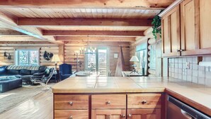 A log cabin interior with a living area, kitchen, and dining space.