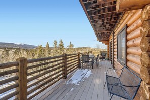 A log cabin with a wooden deck, outdoor seating, and a view of mountains. - Valley View Vistas - Dog-Friendly Cozy Retreat w/ VIEWS! (Nederland)