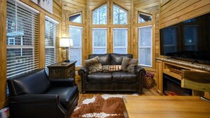 A cozy cabin interior with a leather sofa, a fireplace, and wooden walls. - The Bear Cave tiny cabin experience*3 cabins in 1* (Broken Bow)