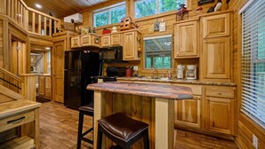 A wooden cabin kitchen with a central island, wooden cabinets, and a refrigerator. - The Bear Cave tiny cabin experience*3 cabins in 1* (Broken Bow)
