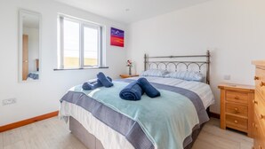A bedroom with a bed, a nightstand, a dresser, a window, and a mirror. - 1 Bed in Southcott (oc-t30813) (Okehampton Hamlets)