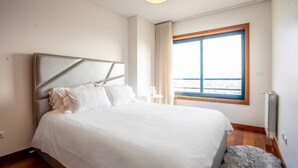 Un moderno cuarto de hotel con una cama grande, vistas de la ciudad a través de una ventana y un radiador en la pared.