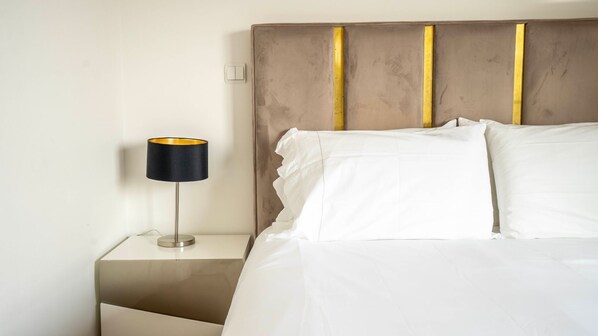 A neatly made bed with white linens and a headboard with vertical gold accents. - Seaside 3BR Flat in Póvoa by LovelyStay (Povoa de Varzim)