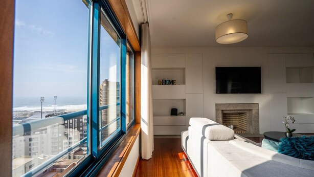 Una sala de estar moderna con un ventanal grande, chimenea y televisor de pantalla plana en la pared.